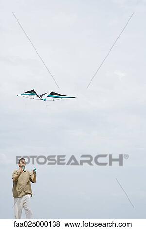 Man flying kite, looking up, three quarter length View Large Photo Image Stock Photo - Man flying kite, looking up, three quarter length. Fotosearch