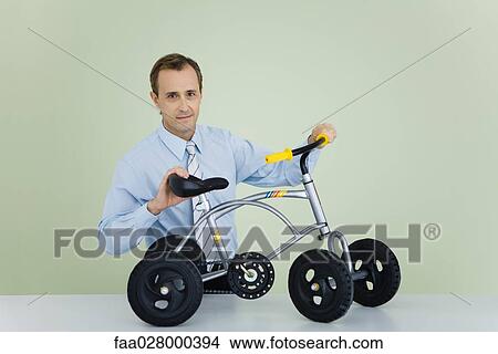 Man holding child's bicycle, looking at camera View Large Photo Image Picture - Man holding child's bicycle, looking at camera. Fotosearch