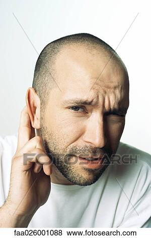 Man holding ear, furrowing brow, looking at camera, close-up View Large Photo Image Stock Photo - Man holding ear, furrowing brow, looking at camera, close-up. Fotosearch
