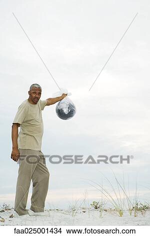Man holding globe in plastic bag, looking at camera View Large Photo Image Picture - Man holding globe in plastic bag, looking at camera. Fotosearch