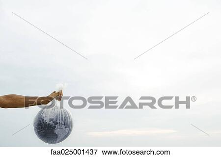 Stock Photo - Man holding globe in plastic bag, cropped view. Fotosearch