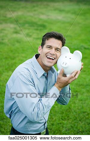 Man holding piggy bank, cheek to cheek, smiling View Large Photo Image Stock Photography - Man holding piggy bank, cheek to cheek, smiling. Fotosearch