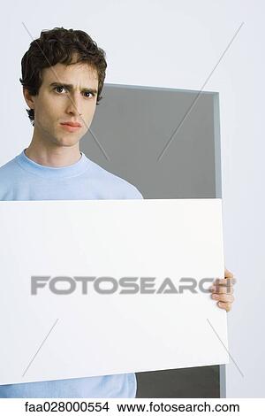 Man holding sign, furrowing brows at camera View Large Photo Image Picture - Man holding sign, furrowing brows at camera. Fotosearch