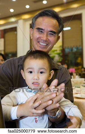 Man holding toddler on lap, clapping, smiling at camera View Large Photo Image Stock Photo - Man holding toddler on lap, clapping, smiling at camera. Fotosearch