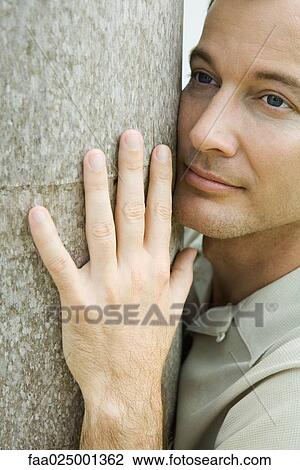 Man hugging tree trunk, looking away, close-up View Large Photo Image Stock Image - Man hugging tree trunk, looking away, close-up. Fotosearch
