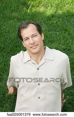Man leaning back in grass, smiling at camera View Large Photo Image Stock Photo - Man leaning back in grass, smiling at camera. Fotosearch