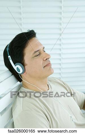 Man listening to headphones, eyes closed, side view View Large Photo Image Stock Photography - Man listening to headphones, eyes closed, side view. Fotosearch