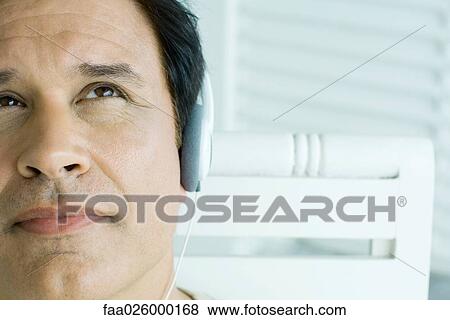 Man listening to headphones, looking up, cropped view View Large Photo Image Stock Photo - Man listening to headphones, looking up, cropped view. Fotosearch