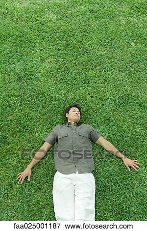 Man lying on back in grass, eyes closed View Large Photo Image Stock Photo - Man lying on back in grass, eyes closed. Fotosearch