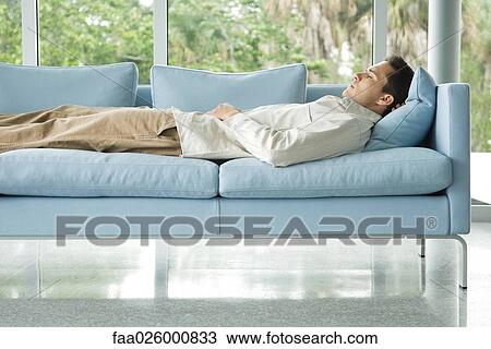 Man lying on couch with hand behind head, eyes closed, side view View Large Photo Image Stock Image - Man lying on couch with hand behind head, eyes closed, side view. Fotosearch