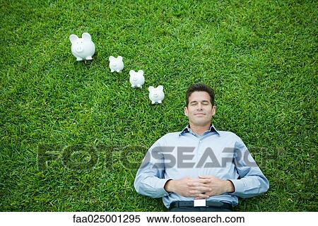 Man lying on grass, line of piggy banks by head View Large Photo Image Stock Photography - Man lying on grass, line of piggy banks by head. Fotosearch