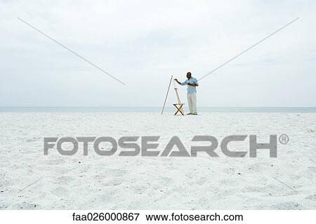 Man painting at the beach, side view, in the distance View Large Photo Image Stock Photo - Man painting at the beach, side view, in the distance. Fotosearch