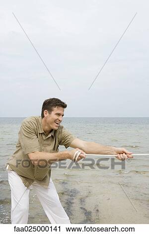 Man playing tug-of-war at the beach, close-up View Large Photo Image Stock Image - Man playing tug-of-war at the beach, close-up. Fotosearch