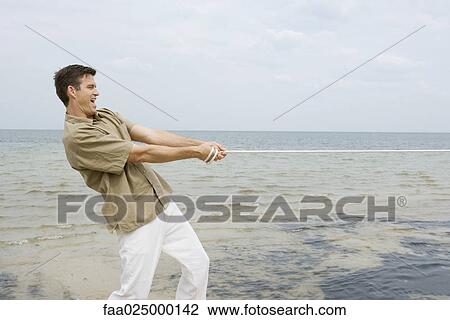Man playing tug-of-war at the beach, side view View Large Photo Image Stock Image - Man playing tug-of-war at the beach, side view. Fotosearch
