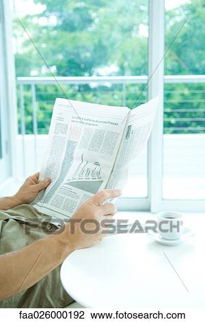 Man reading newspaper at table, cropped view View Large Photo Image Stock Image - Man reading newspaper at table, cropped view. Fotosearch