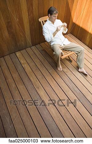 Man sitting in lounge chair looking at starfish, high angle view View Large Photo Image Stock Image - Man sitting in lounge chair looking at starfish, high angle view. Fotosearch