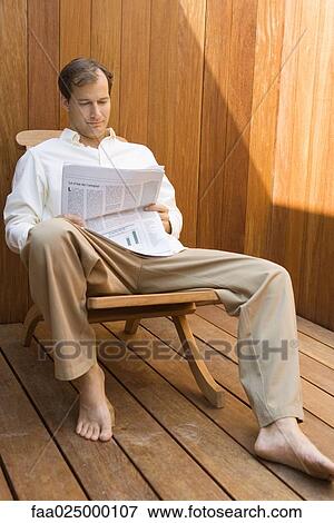 Man sitting in lounge chair reading newspaper View Large Photo Image Stock Photo - Man sitting in lounge chair reading newspaper. Fotosearch