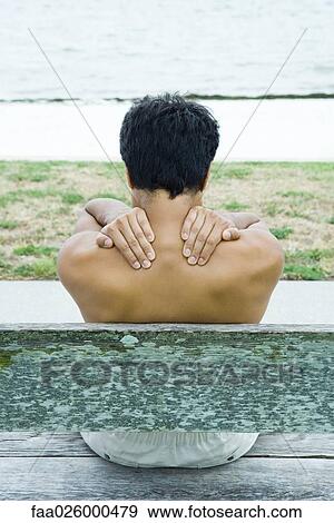 Man sitting on bench, hands on shoulders, rear view View Large Photo Image Stock Photo - Man sitting on bench, hands on shoulders, rear view. Fotosearch