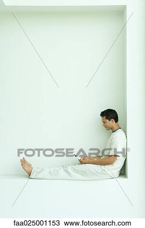 Man sitting on ledge using cell phone, full length, side view View Large Photo Image Stock Image - Man sitting on ledge using cell phone, full length, side view. Fotosearch