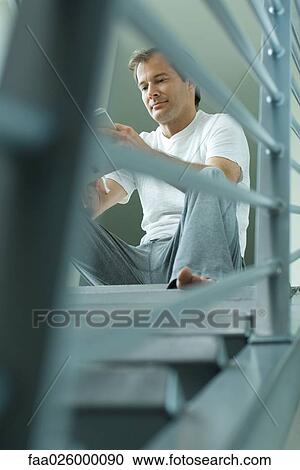 Man sitting on stairs reading book, low angle view View Large Photo Image Stock Image - Man sitting on stairs reading book, low angle view. Fotosearch