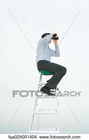 Man sitting on top of ladder looking through binoculars, side view View Large Photo Image Picture - Man sitting on top of ladder looking through binoculars, side view. Fotosearch