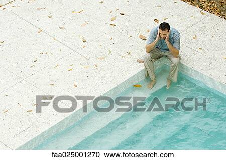Man sitting with feet in pool, holding head, high angle view View Large Photo Image Stock Image - Man sitting with feet in pool, holding head, high angle view. Fotosearch
