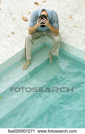 Man sitting with feet in pool, holding head, high angle view View Large Photo Image Stock Image - Man sitting with feet in pool, holding head, high angle view. Fotosearch