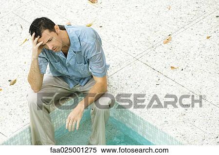 Man sitting with feet in pool, holding head, high angle view View Large Photo Image Stock Photography - Man sitting with feet in pool, holding head, high angle view. Fotosearch