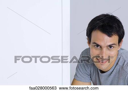 Stock Image - Man smirking at camera, portrait. Fotosearch