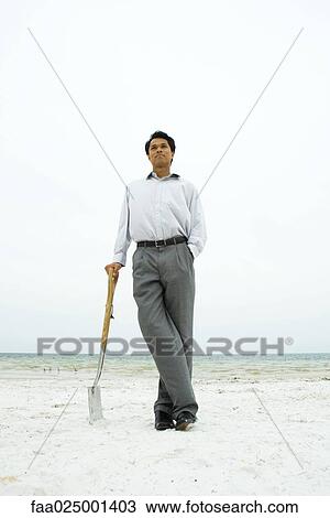 Man standing at the beach, leaning against shovel, hand in pocket View Large Photo Image Stock Image - Man standing at the beach, leaning against shovel, hand in pocket. Fotosearch