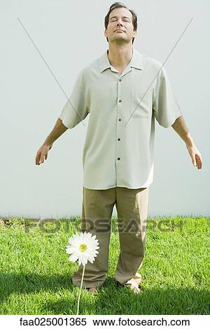 Man standing behind flower, arms out, eyes closed View Large Photo Image Stock Photography - Man standing behind flower, arms out, eyes closed. Fotosearch