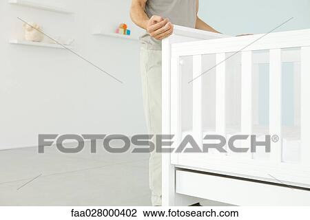 Man standing beside crib in nursery, cropped view View Large Photo Image Stock Image - Man standing beside crib in nursery, cropped view. Fotosearch