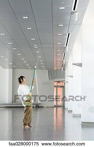 Man standing in lobby, listening to headphones, playing air guitar with broom View Large Photo Image Stock Photography - Man standing in lobby, listening to headphones, playing air guitar with broom. Fotosearch