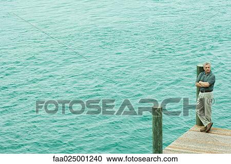 Man standing on corner of dock, looking away, high angle view View Large Photo Image Stock Image - Man standing on corner of dock, looking away, high angle view. Fotosearch