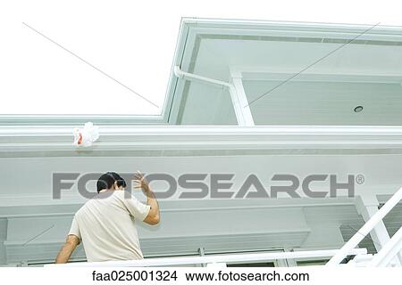 Man standing on deck, throwing litter over shoulder, low angle view View Large Photo Image Picture - Man standing on deck, throwing litter over shoulder, low angle view. Fotosearch