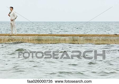 Man standing on jetty, looking at sea, in mid distance View Large Photo Image Stock Photography - Man standing on jetty, looking at sea, in mid distance. Fotosearch