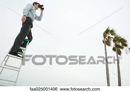 Man standing on ladder, looking through binoculars, low angle view View Large Photo Image Stock Photograph - Man standing on ladder, looking through binoculars, low angle view. Fotosearch