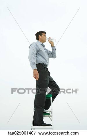 Man standing on top of ladder, drinking bottled water, side view View Large Photo Image Stock Photo - Man standing on top of ladder, drinking bottled water, side view. Fotosearch