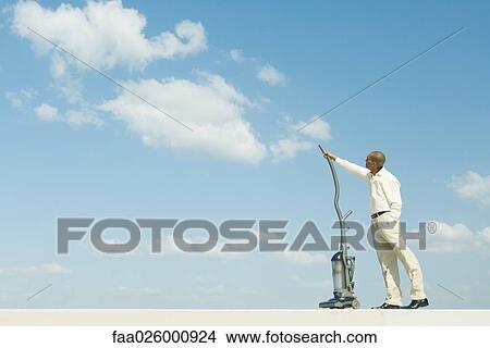 Man standing out doors, vacuuming clouds, side view View Large Photo Image Picture - Man standing out doors, vacuuming clouds, side view. Fotosearch