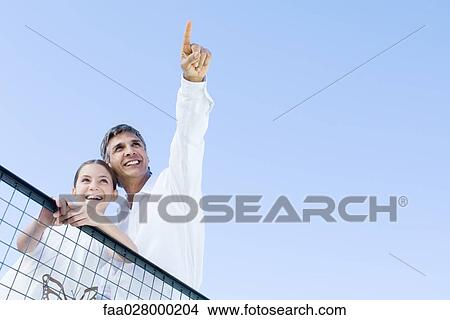 Man standing outdoors with daughter, pointing at the sky, both looking up and smiling, low angle view View Large Photo Image Picture - Man standing outdoors with daughter, pointing at the sky, both looking up and smiling, low angle view. Fotosearch