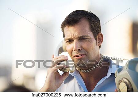 Man talking on landline phone, cord wrapped around his neck, close-up View Large Photo Image Stock Photography - Man talking on landline phone, cord wrapped around his neck, close-up. Fotosearch