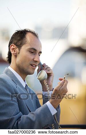Man using landline phone, looking at damaged end of cord, close-up View Large Photo Image Stock Photograph - Man using landline phone, looking at damaged end of cord, close-up. Fotosearch