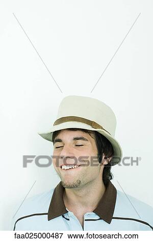 Stock Photo - Man wearing hat, making faces, eyes closed. Fotosearch