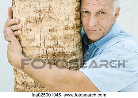 Mature man hugging tree trunk, portrait View Large Photo Image Stock Photography - Mature man hugging tree trunk, portrait. Fotosearch