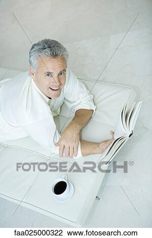 Mature man lying on chaise longue holding book, looking up at camera, high angle view View Large Photo Image Stock Image - Mature man lying on chaise longue holding book, looking up at camera, high angle view. Fotosearch