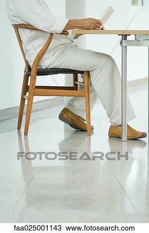 Mature man sitting at table reading book, chest down, side view View Large Photo Image Stock Image - Mature man sitting at table reading book, chest down, side view. Fotosearch
