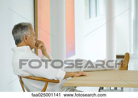 Mature man sitting at table with leg up, hand under chin View Large Photo Image Stock Image - Mature man sitting at table with leg up, hand under chin. Fotosearch