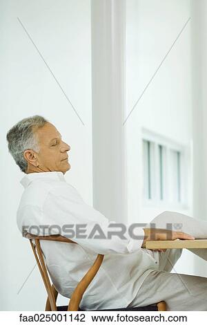 Mature man sitting at table with leg up, hand under chin View Large Photo Image Stock Image - Mature man sitting at table with leg up, hand under chin. Fotosearch