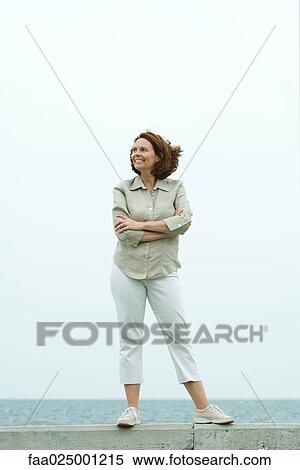 Mature woman standing in front of ocean horizon, looking away, smiling, full length View Large Photo Image Stock Photography - Mature woman standing in front of ocean horizon, looking away, smiling, full length. Fotosearch
