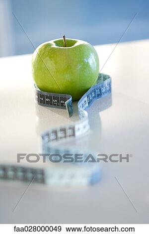 Measuring tape wrapped around green apple, close-up View Large Photo Image Stock Photo - Measuring tape wrapped around green apple, close-up. Fotosearch